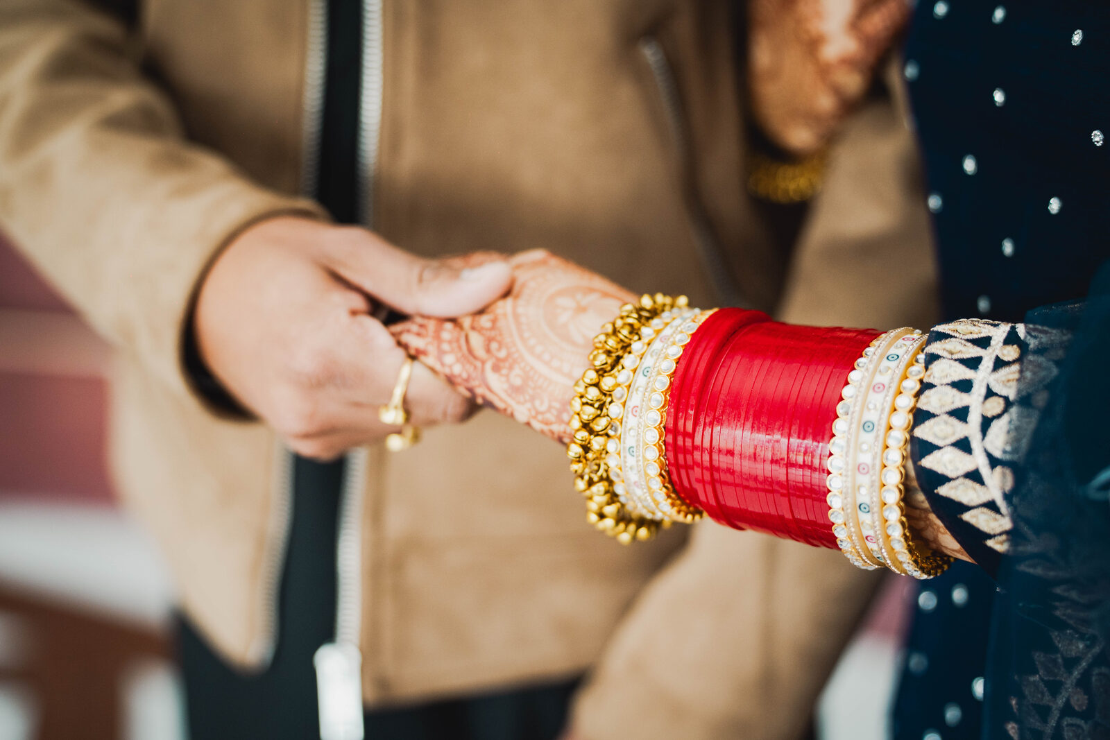Hands with red and gold bangles holding each other